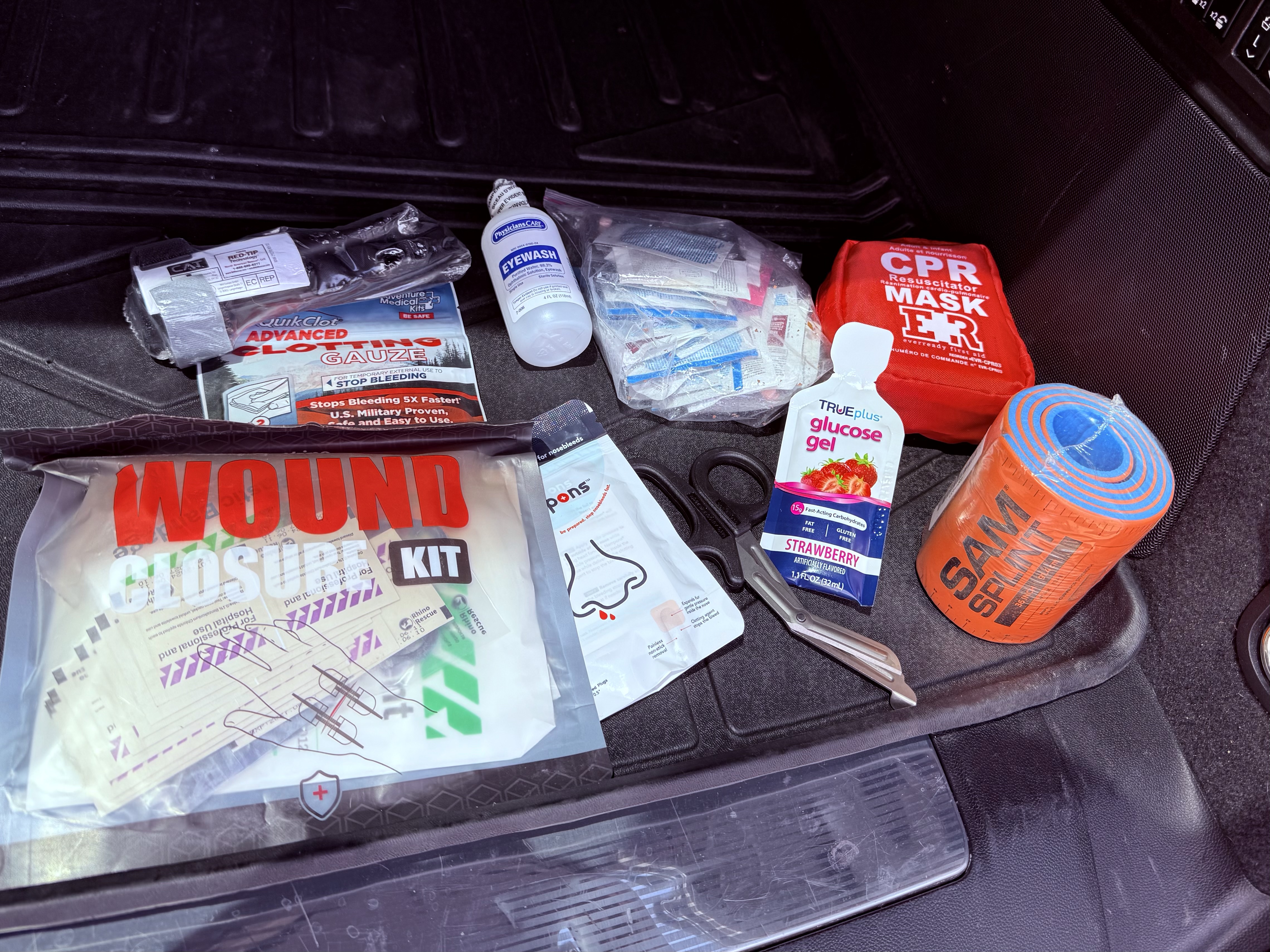First aid kit contents including tourniquet, QuikClot gauze, CPR mask, SAM splint, and wound closure kit — Colorado Luxury Driver luxury chauffeur Denver mountain transportation